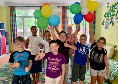 Children happy in a group, holding up balloons