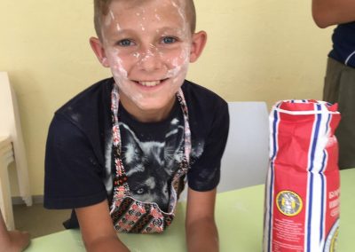 Boy in cooking workshop, with flour on his face smiling