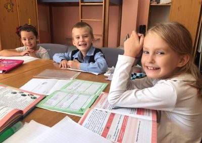 Children doing school work together smiling